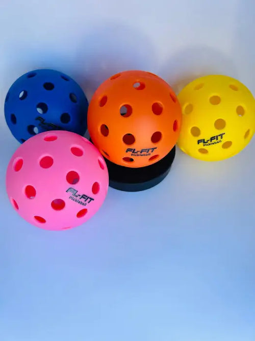 Balle de pickleball mulicouleur FL-FIT avec trous sur socle noir, fond bleu clair